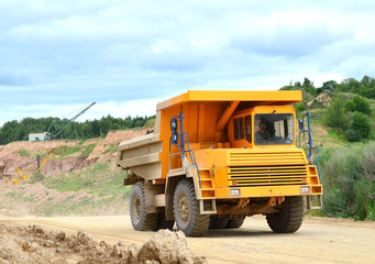 Big yellow mining truck working in the limestone open-pit. Loading and transportation of minerals in the dolomite mining quarry. Belarus, Vitebsk, in the largest dolomite deposit, quarry "Gralevo"
