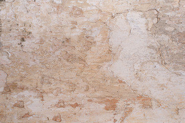 Grunge background with old stucco wall texture of beige color. cracks