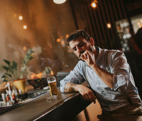 Man drinking beer and smoking cigarette at pub