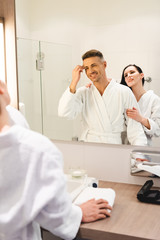 Obraz premium selective focus of boyfriend combing hair and smiling girlfriend hugging him in hotel