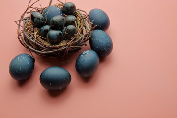 Eggs painted with a blue stone lie in a nest on a pink background, Easter.