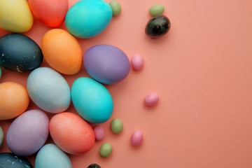 Multicolored eggs and candies lie on a pink background.