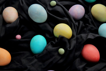 Fototapeta na wymiar Colorful eggs and lollipops on a black background, Easter.
