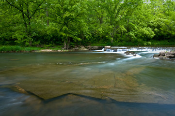 pring landscape with picturesque creek and waterfall.