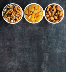 Dried fruits in white bowls on a dark background to maintain cardiovascular health top view with empty place
