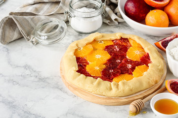 Delicious galette with red blood oranges on a marble table. Homemade citrus  tart.  Healthy dessert. Copy space. Selective focus.