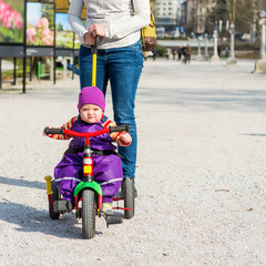 Cute baby girl enjoying her first bycicle ride with mothers help.