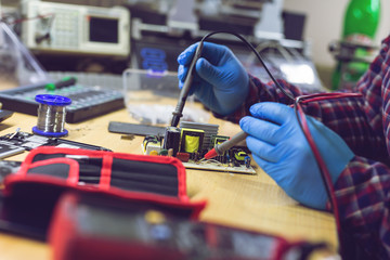 Technician engineer in workshop. Repairman is checking circuit board of electronic device.