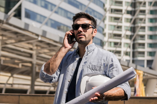 engineer working with documents at construction site.engineers man working at building site by mobile phone. - Powered by Adobe