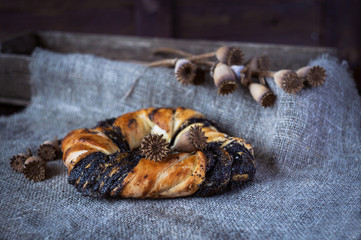 Poppy seed roll on a dark background and burlap with poppy heads