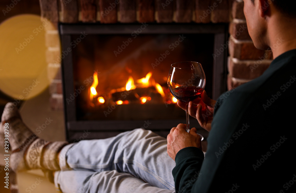 Canvas Prints man with glass of wine near fireplace at home, closeup