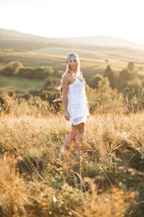 Fototapeta na wymiar Beautiful hippie blonde girl in dress on nature, summer field. Boho fashion style