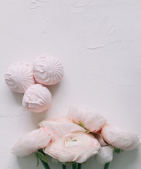 Fototapeta na wymiar Spring wallpaper. Pink rose flowers and marshmallows on a white background. Flowers composition. Flat lay, top view, copy space. 