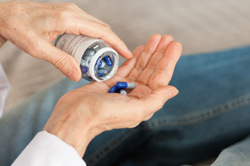 Female hand close up holding a medicine, elderly woman hands with pill on spilling pills out of bottle .