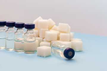 Sugar addiction, insulin resistance, unhealthy diet, sugar cubes and bottles of insulin on blue background, diabetes protection medical concept, top view.