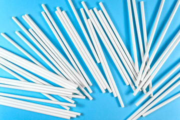 A lot of white paper tubes are scattered randomly on a blue background. The view cocktail tube texture. Reasonable consumption. Close up straw clipart pattern. Eco friendly organic garbage. Zero waste