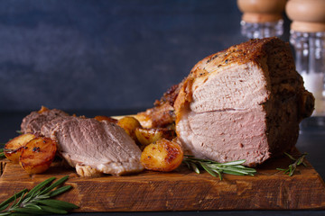 Roast leg of lamb with potatoes and rosemary on serving wooden board © freeskyline