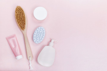  Brush for dry massage, soap, body cream over pink background. flat lay top view