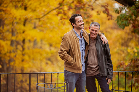 Happy young man standing with father in balcony during autumn