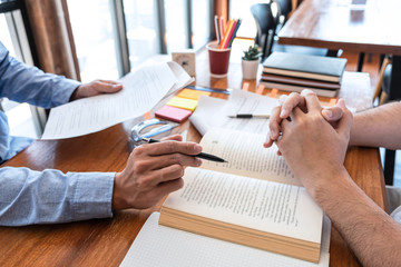 Teaching helping and study course, Team of young teacher or tutor helps students to learning in classroom for homework a test or exam at desk with papers