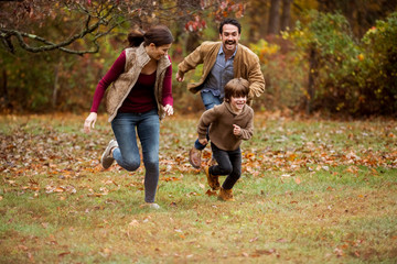 Fototapeta premium Happy parents playing with son in backyard during autumn