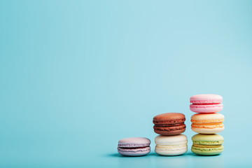 Multicolored French macaroni macaroni cookies are arranged in a pyramid on a blue background.
