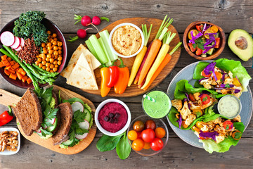 Healthy lunch table scene with nutritious Buddha bowl, vegetables, sandwiches, lettuce wraps and...