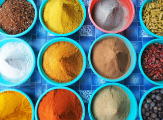 Top view of a variety of colorful spices laid out in blue cups. Heritage of India