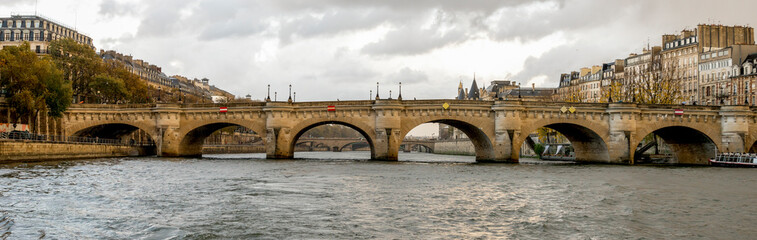 Obraz premium Scenic arches of Pont Neuf bridge and Paris cityscape while cruising on river Seine, France
