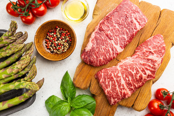 Raw Steak with green asparagus on white background, top view
