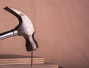 A metal hammer driving a tip into a wooden cabinet. Horizontal format.