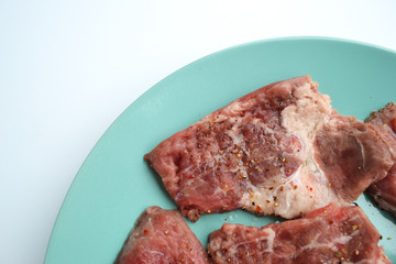 Pieces of meat ready for marinade lying on a plate with spices