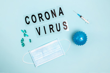 Abstract virus strain model of Coronavirus disease COVID-19, pills, syringe and mask on blue with copy space.