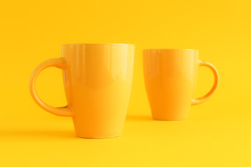 Two yellow coffee cups on yellow background