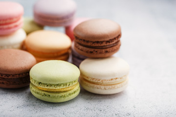 Multicolored macaroni cookies lie on a gray stone slab.