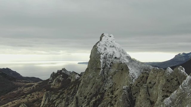 view from above on the mountain range on the sea coast with scant vegetation and snow on an overcast day