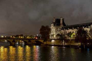 A night view of Louvre museum building near Pont Royal Bridge, Paris, France