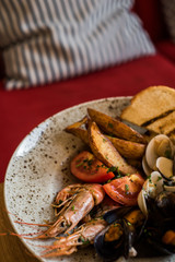 A plate with a variety of seafood stands on a table in a restaurant