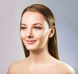 Beautiful smiling girl with perfect skin and cream dots. Over blue background.