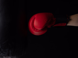 red boxing glove hitting the punching bag on black background