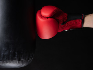 red boxing glove hitting the punching bag on black background