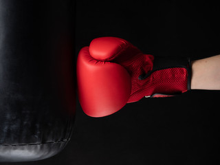 red boxing glove hitting the punching bag on black background