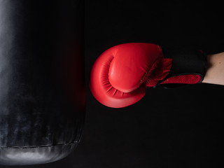 red boxing glove hitting the punching bag on black background