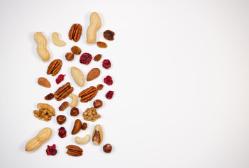 Mixed nuts and dried fruits in wooden bowl on white background, copy space