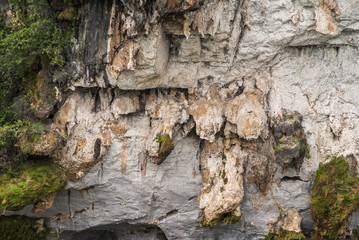 Guilin, China - May 10, 2010: Along Li River. Closeup of Green foliage and hanging white, brown and black rock sheets on verticla cliff.