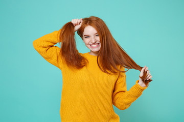 Cheerful young redhead woman girl in yellow sweater posing isolated on blue turquoise background...