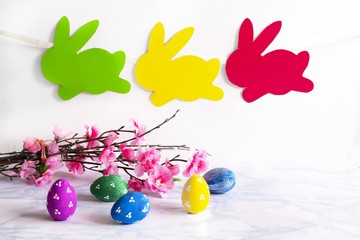 Fototapeta na wymiar Colorful eggs with handmade bunny easter garland on netural background.