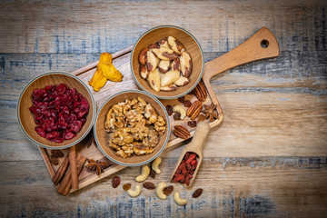 Mixed nuts and dried fruits in wooden bowl on wood background, copy space
