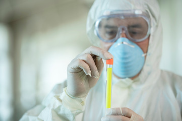 Scientist wearing protective gear holding a  test result for coronavirus