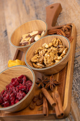 Mixed nuts and dried fruits in wooden bowl on wood background, copy space